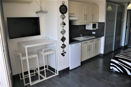 Il comprend une petite cuisine avec une table et une télévision. dans l'établissement Studio 321, Héliopolis AB au village naturiste, au Cap d'Agde