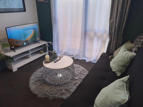 a living room with a couch and a tv and a table at Hall Street Haven in Te Awamutu