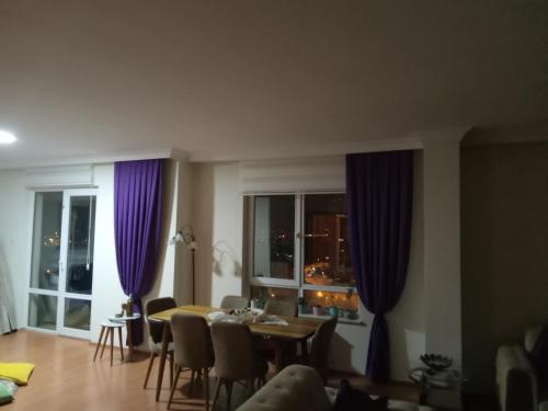 een woonkamer met paarse gordijnen en een tafel en stoelen bij LAFAMILA HOUSE in Ankara