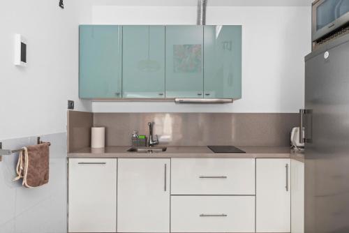 a kitchen with white cabinets and a sink at AleSol Tenerife in Playa Fañabe