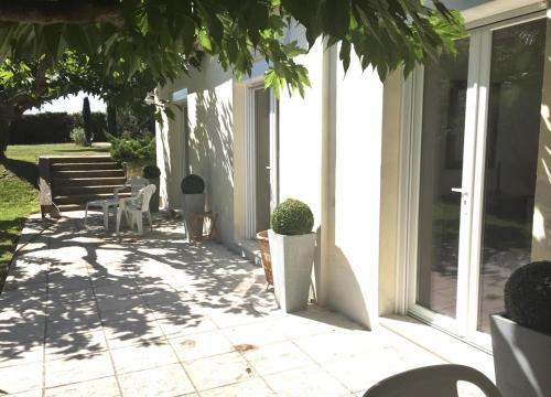 een patio met een tafel en stoelen op een huis bij Maison climatisée, 3 chambres, 2 étoiles, tout confort in Noves