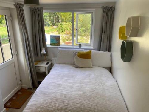 a bedroom with a large white bed with a window at Light airy comfy small double room with en-suite in Falmouth