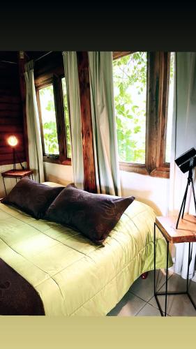 a bed sitting in a room with two windows at Posada del Viento in Tandil