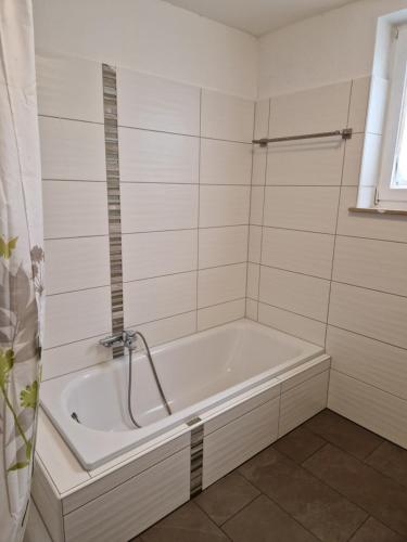 eine weiße Badewanne in einem weiß gefliesten Bad in der Unterkunft Sson Rentals in Detmold