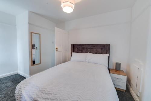 Schlafzimmer mit einem großen weißen Bett mit einem Kopfteil aus Holz in der Unterkunft Farmway lodge in Middleton