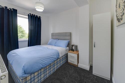 a bedroom with a bed with blue sheets and a window at Farmway lodge in Middleton