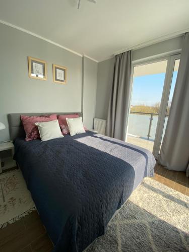 a bedroom with a large bed with a large window at Nowoczesny apartament przy ul Plażowej, Sarbinowo in Sarbinowo