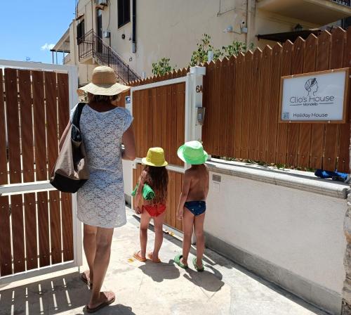 Une femme et deux enfants regardent une clôture dans l'établissement Clio's House - Mondello, à Mondello
