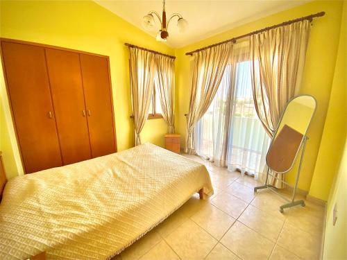 a bedroom with a bed and a chair and windows at Villa Victoria Ayia Napa in Ayia Napa