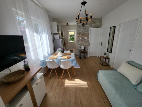 a living room with a table with chairs and a tv at Apartman Planinić in Rogoznica