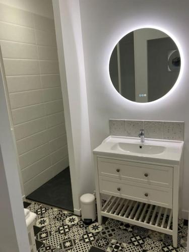 une salle de bain blanche avec un lavabo et un miroir dans l'établissement La Petite Maison, à Châteauroux