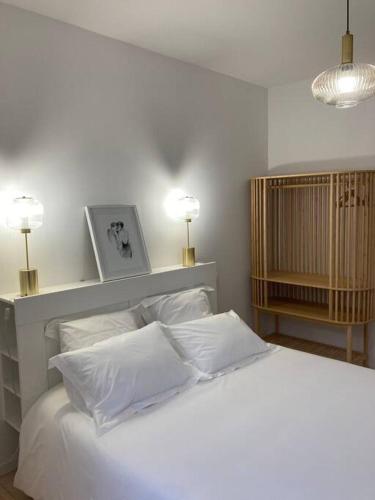 une chambre avec un lit blanc avec des oreillers et deux lampes dans l'établissement La Petite Maison, à Châteauroux