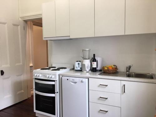 a white kitchen with a stove and a sink at Charming Federation style home minutes from CBD in Perth