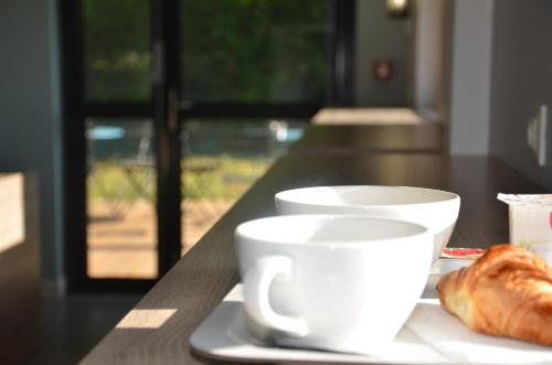 Dos tazas de café y un plato de croissants sobre una mesa. en Eklo Hotels Le Mans, en Le Mans
