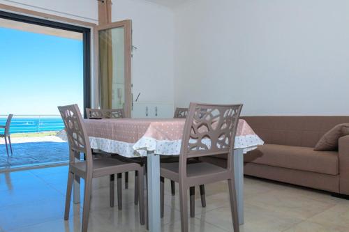 a dining room table with two chairs and a couch at Villa Terrazza sul Golfo in Monte SantʼAngelo
