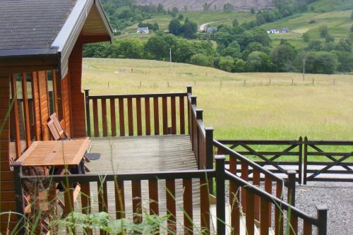 - une terrasse en bois sur le côté d'une maison avec un champ dans l'établissement Bothan a' Bhile, à Bohenie