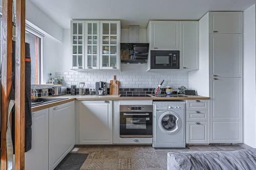 une cuisine avec des armoires blanches et une machine à laver dans l'établissement Charme et confort - proche Tour Eiffel Paris 16, à Paris