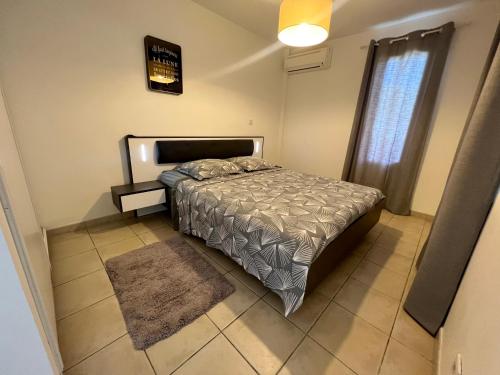 a bedroom with a bed and a window and a rug at Appartement Au Bord de Mer in Le Moule