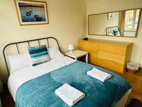 een slaapkamer met een bed met twee handdoeken erop bij London Mackenzie Apartment in Londen