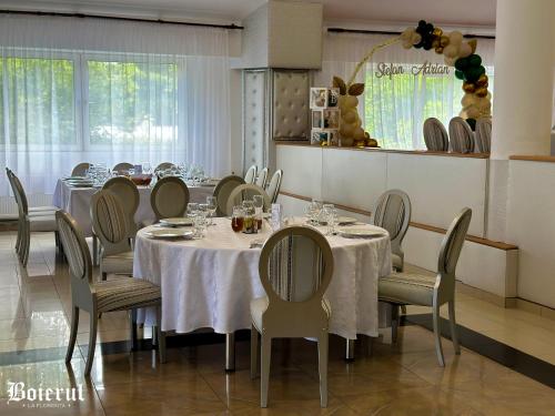 a dining room with white tables and chairs and a window at Boierul la Florenta in Dej