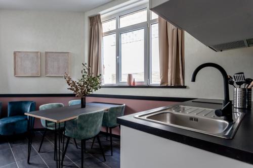 een keuken met een wastafel en een tafel met stoelen bij Hey - Aparthotel Brussels in Brussel