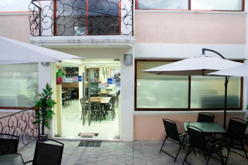 Hotel Tlaxcala في Tlaxcala de Xicohténcatl: مطعم فارغ بطاولات وكراسي ومظلات