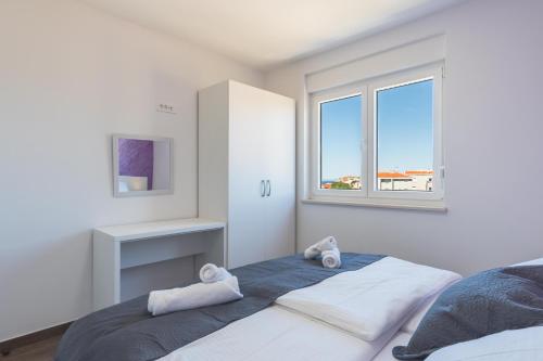 a white bedroom with a bed and a window at Villa Lavanda in Novalja