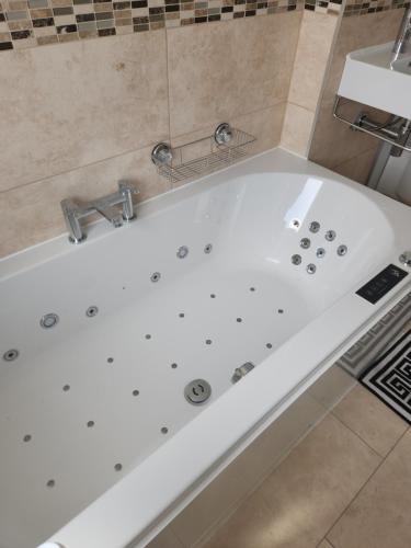 a white bath tub with a sink in a bathroom at Cosy 3 Bedroom Home in Notts in Nottingham