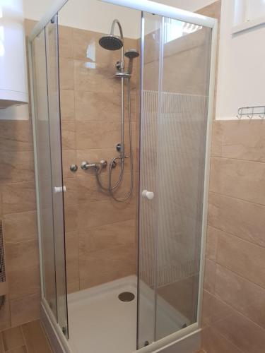 a shower with a glass door in a bathroom at Henrietta Apartmanház in Zalakaros