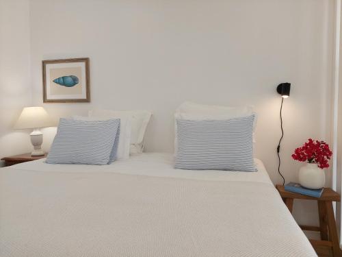 a bed with two blue and white pillows on it at Estúdio Lagoa Azul in Vila Nova de Milfontes