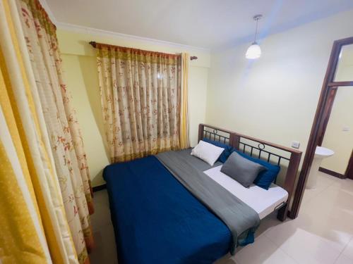 um quarto com uma cama com lençóis e almofadas azuis em Beckys Apartment in down Town Arusha 