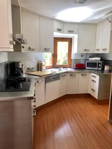 a kitchen with white cabinets and a wooden floor at Villa Ávilla. Luxo e Charme. in Cascais