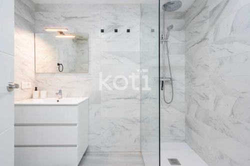 ein weißes Bad mit einer Dusche und einem Waschbecken in der Unterkunft Koti Rentals - Lubina 2 in Fuengirola