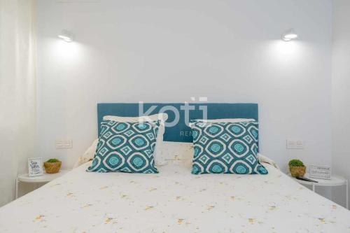 Schlafzimmer mit einem Bett mit blauen und weißen Kissen in der Unterkunft Koti Rentals - Lubina 2 in Fuengirola