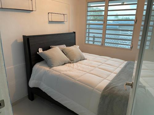ein Bett mit weißer Bettwäsche und Kissen in einem Schlafzimmer in der Unterkunft Luquillo Mar Paradise in Luquillo