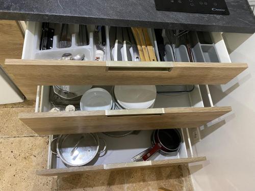 un tiroir de cuisine rempli de tasses et d'ustensiles dans l'établissement Studios villa coincoin, à La Garde