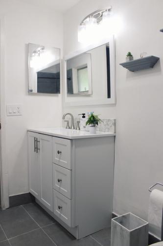 a white bathroom with a sink and two mirrors at Cozy 3BR Home near Weeki Wachee in Spring Hill