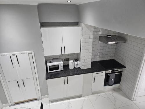 una pequeña cocina con armarios blancos y microondas en Bridge Apartment, en Liverpool