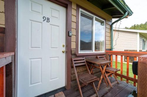 a porch with a white door and chairs on a house at Elk Meadow Cabins 9B Prairie Creek - Single Room in Orick