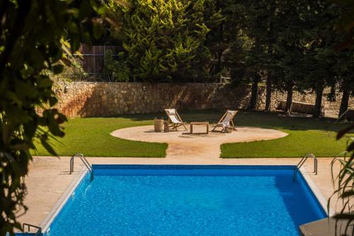a swimming pool with two lawn chairs and a table at Theros Retreat in Spartia