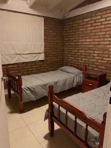 2 camas en una habitación con una pared de ladrillo en Cabañas las Calandrias en Potrero de los Funes