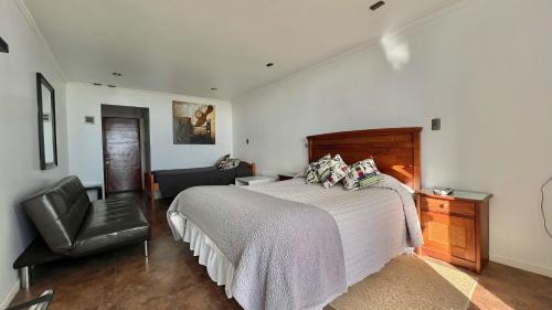 a bedroom with a large bed and a chair at Hotel Del Valle Quilimari in Pichidangui