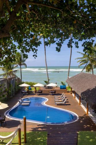 a swimming pool next to the beach with chairs and umbrellas at Flor de Lis Exclusive Hotel in Maceió
