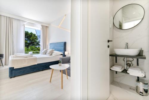 a bedroom with a bed and a sink and a mirror at Aurora Beachfront Luxury Rooms&Suites in Brela