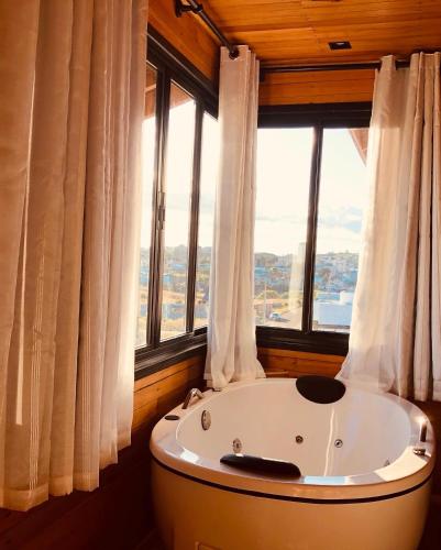 a large bath tub in a room with windows at Recanto Ar da Serra in São Joaquim