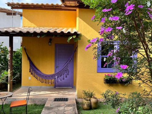 una casa amarilla con puerta morada y ventana en Chalés Calima en Lençóis