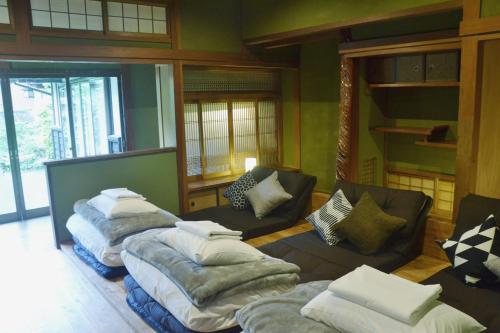Habitación con 3 camas y sillas. en 野窓 Nomadノマド Tsuwano GuestHouse & Cafe Lounge en Tsuwano