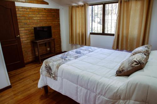 - une chambre avec un lit blanc et une télévision dans l'établissement Wicz Apart Iguazú, à Puerto Iguazú