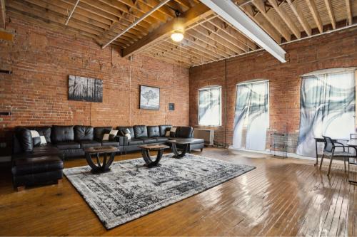 una sala de estar con una pared de ladrillo, sofás y mesas. en FULLY EQUIPPED FOR THE 2024 NFL DRAFT!!! - Downtown Detroit Loft en Detroit