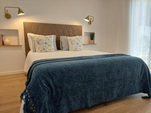 a bedroom with a large bed with a blue blanket at Lagoa azul guest house II in Vila Nova de Milfontes